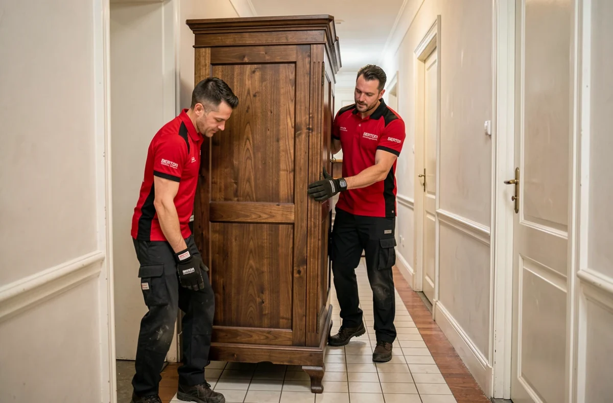 Deux déménageurs Berton manœuvrant une armoire dans un couloir d'appartement
